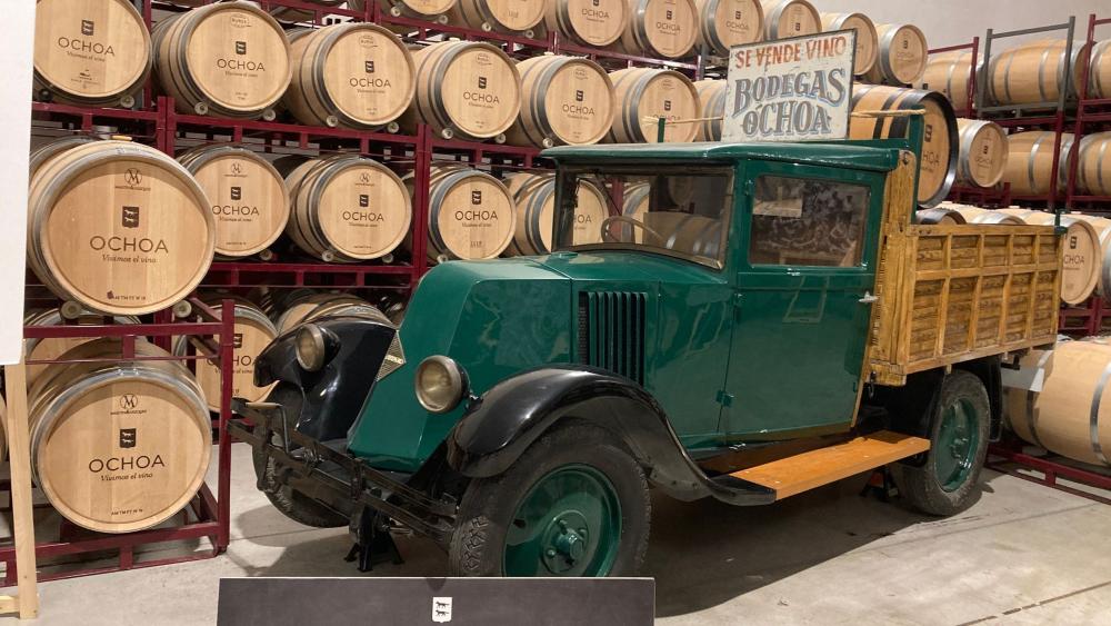coche antiguo con barricas de vino al fondo